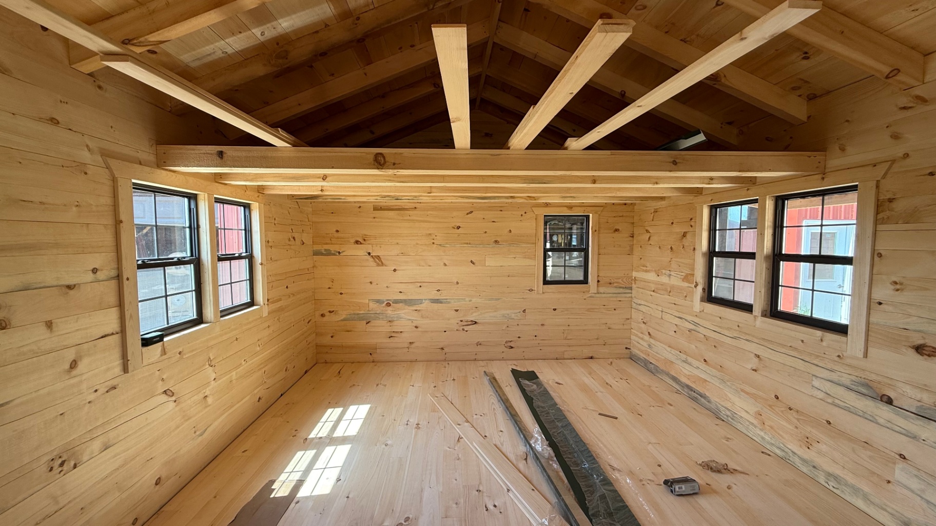 Finished cabin interior with exposed rafters and black-frame windows