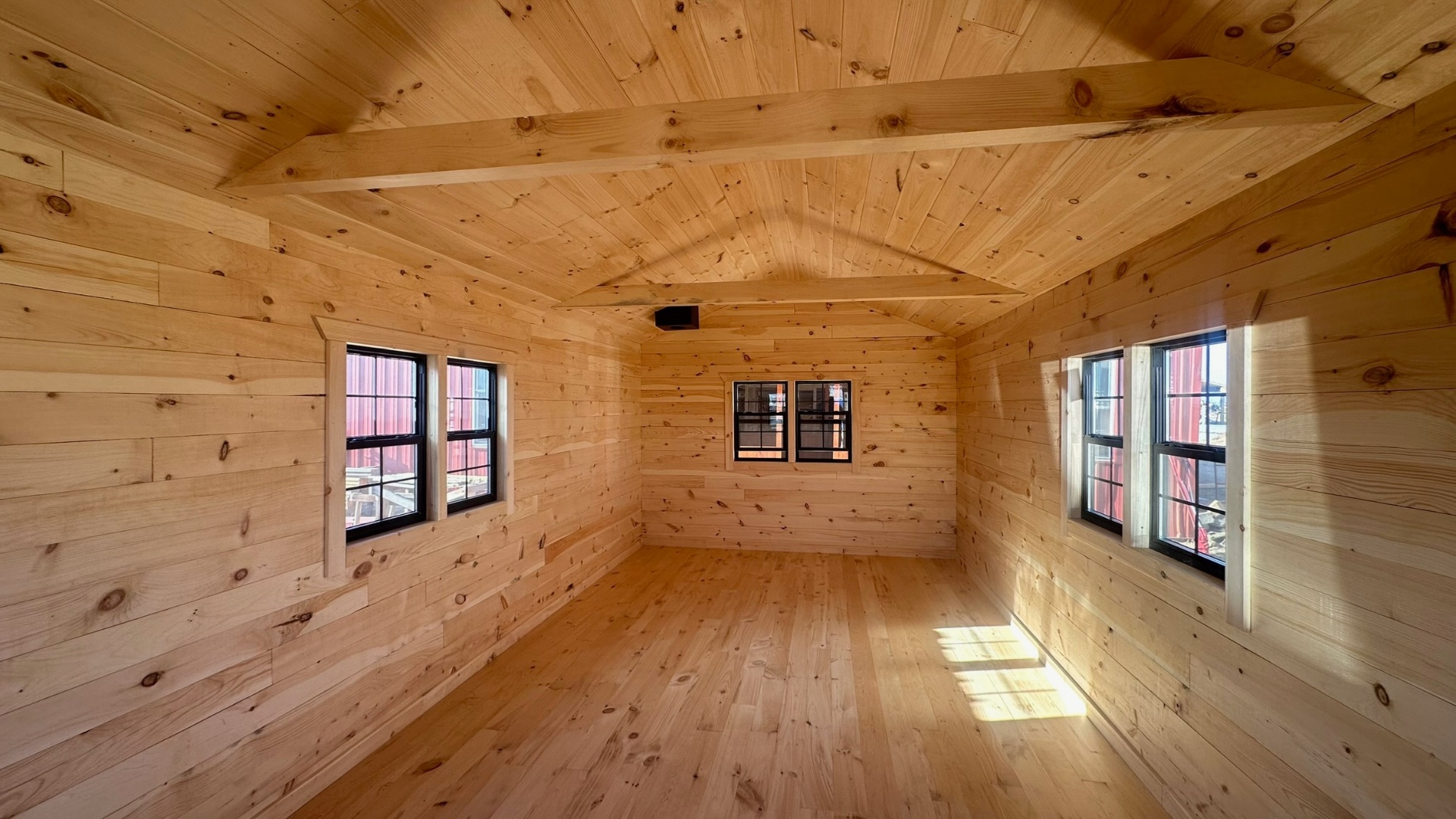 Bright pine interior with vaulted ceiling and black-frame windows