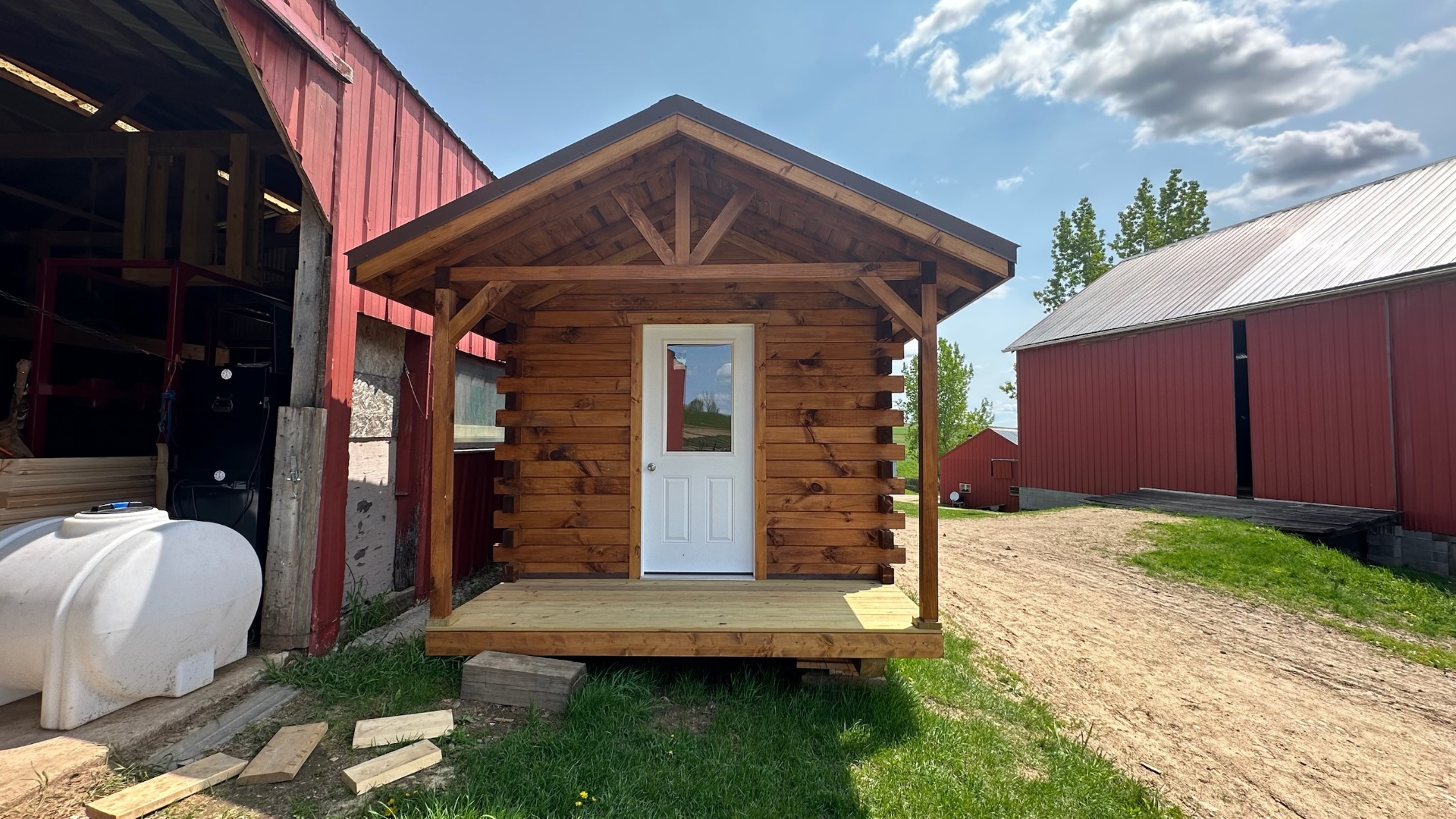 Small stained log cabin with covered porch at the shop