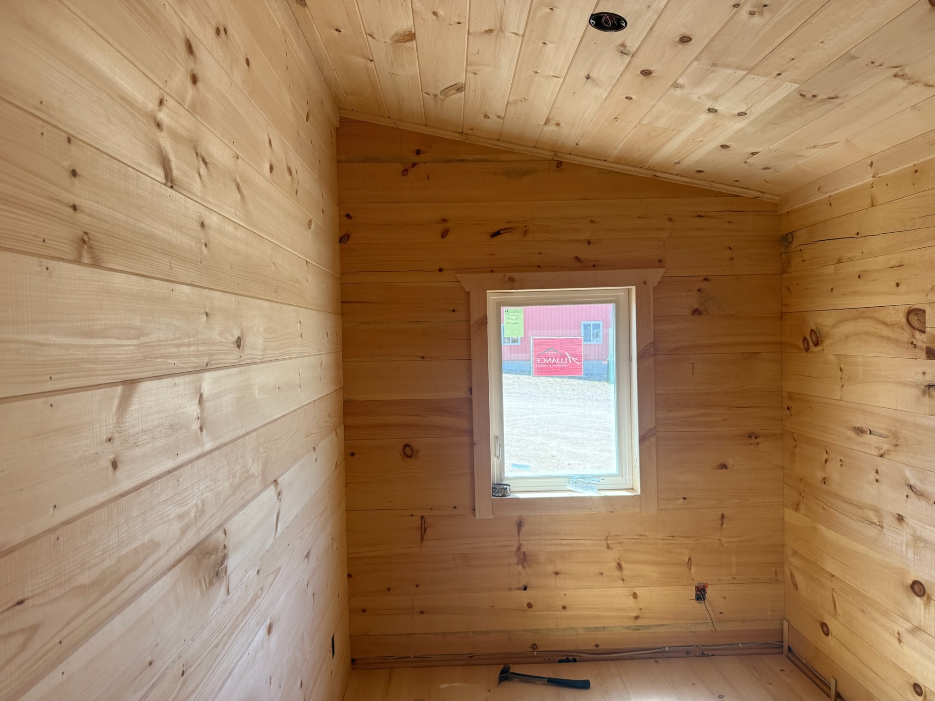Pine-paneled cabin alcove with vaulted ceiling and small window
