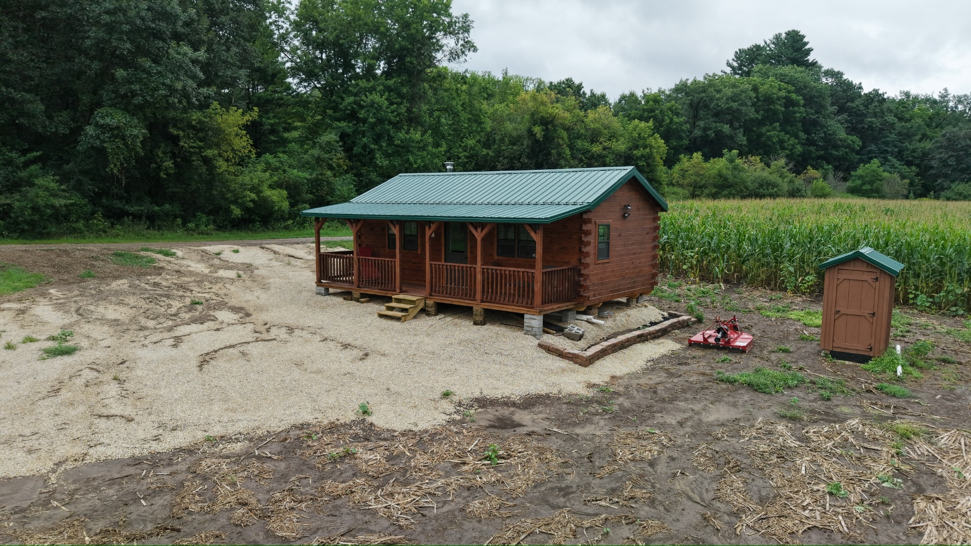 Finished log cabin with green metal roof in a field