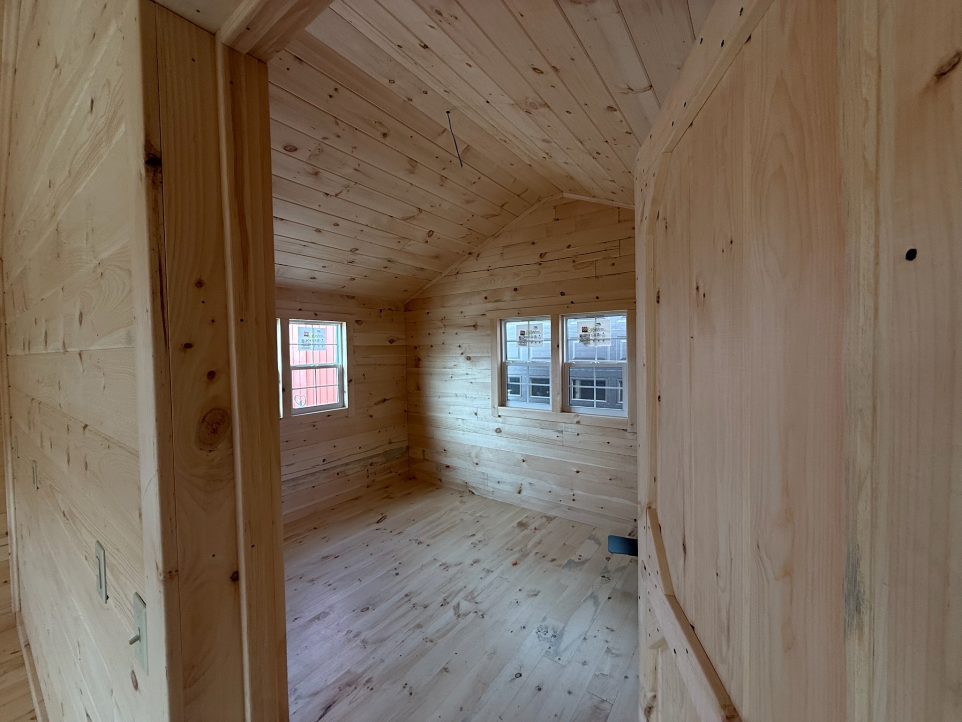 Cabin bedroom with vaulted pine ceiling and double windows