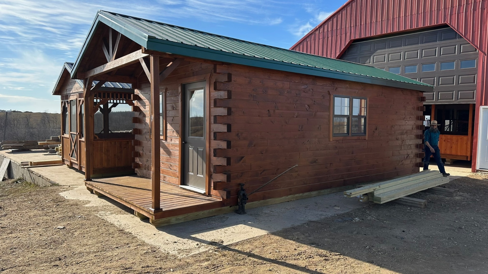 Large stained log cabin with green metal roof at the shop